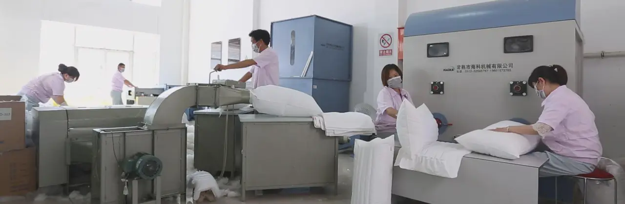 Workers filling and finishing white hospitality pillows